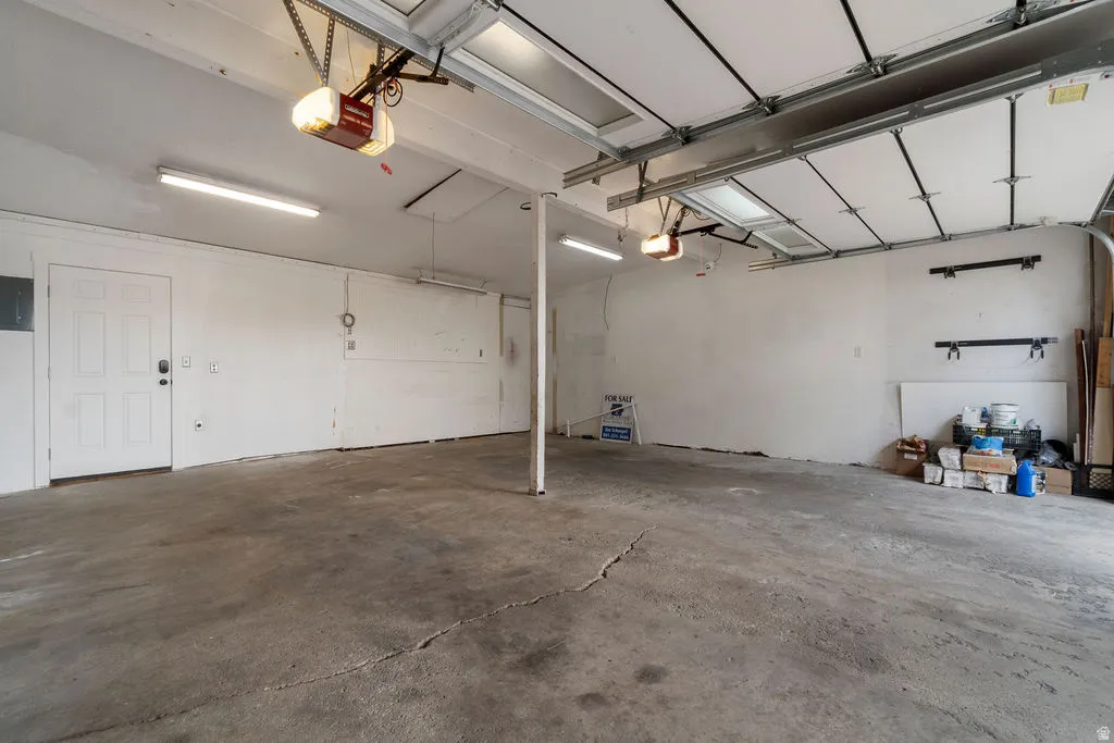 Spacious garage featuring concrete flooring, white walls, and multiple overhead fluorescent light fixtures