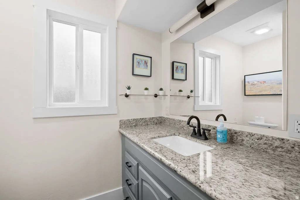 Bathroom vanity featuring a stone countertop, undermount sink, and matte black faucet