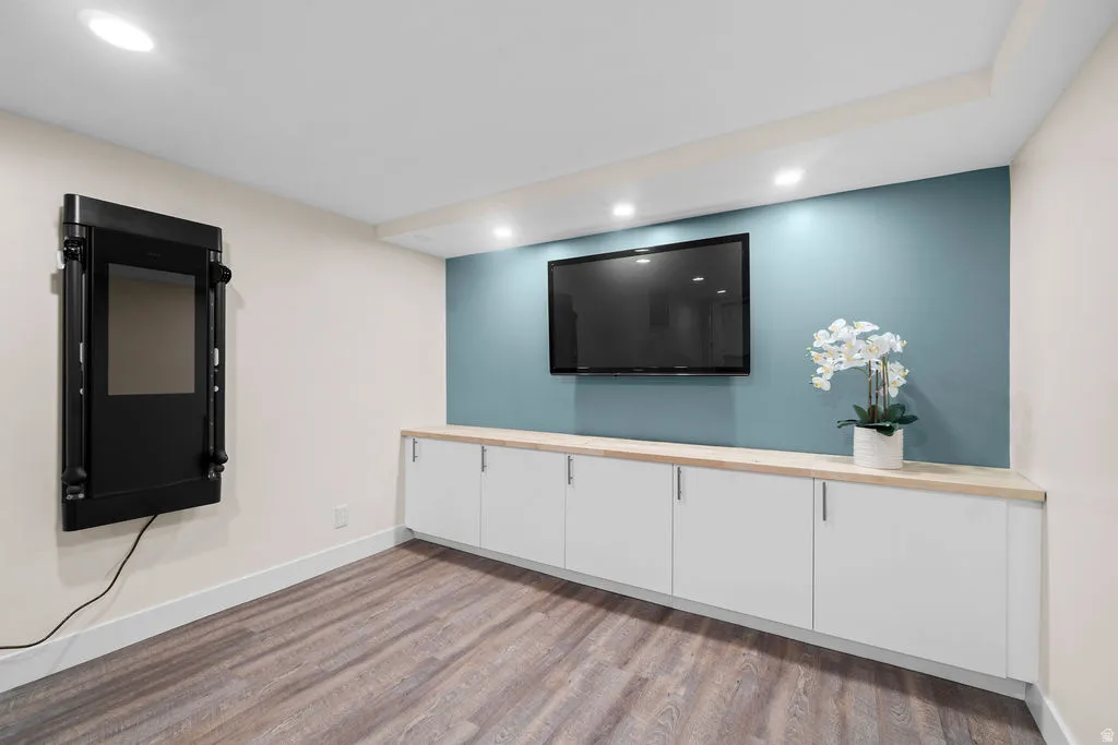 Integrated entertainment wall featuring a wall-mounted television, built-in white cabinetry, and a light wood-finish countertop