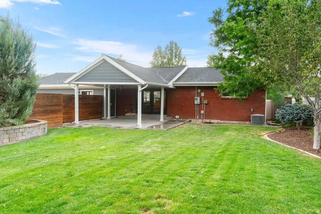 Expansive rear yard featuring a covered patio, red brick exterior, and a horizontal wood privacy screen