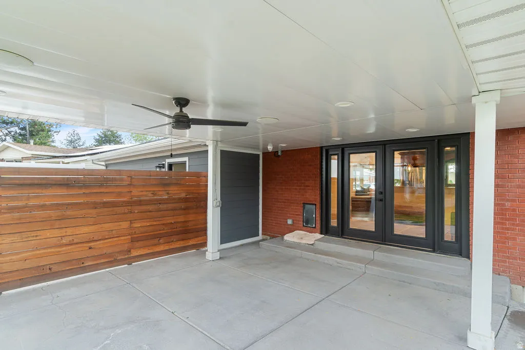 Covered patio with a concrete surface, featuring a ceiling fan, recessed lighting, and a slatted wood privacy wall