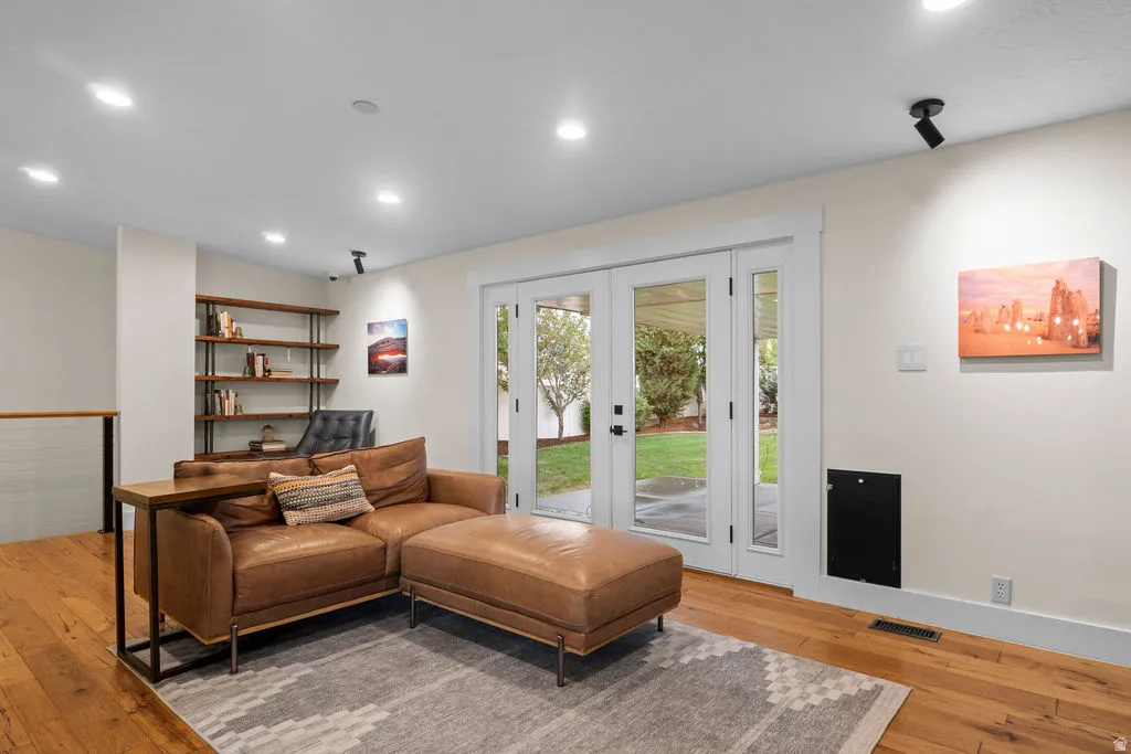 Recessed lighting illuminates this room featuring wood-finish flooring and a built-in wall shelf
