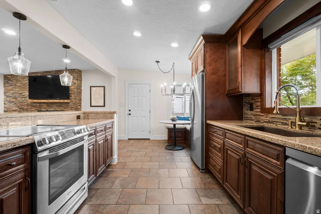 Kitchen featuring wood cabinetry, light-toned stone countertops, and stainless steel appliances