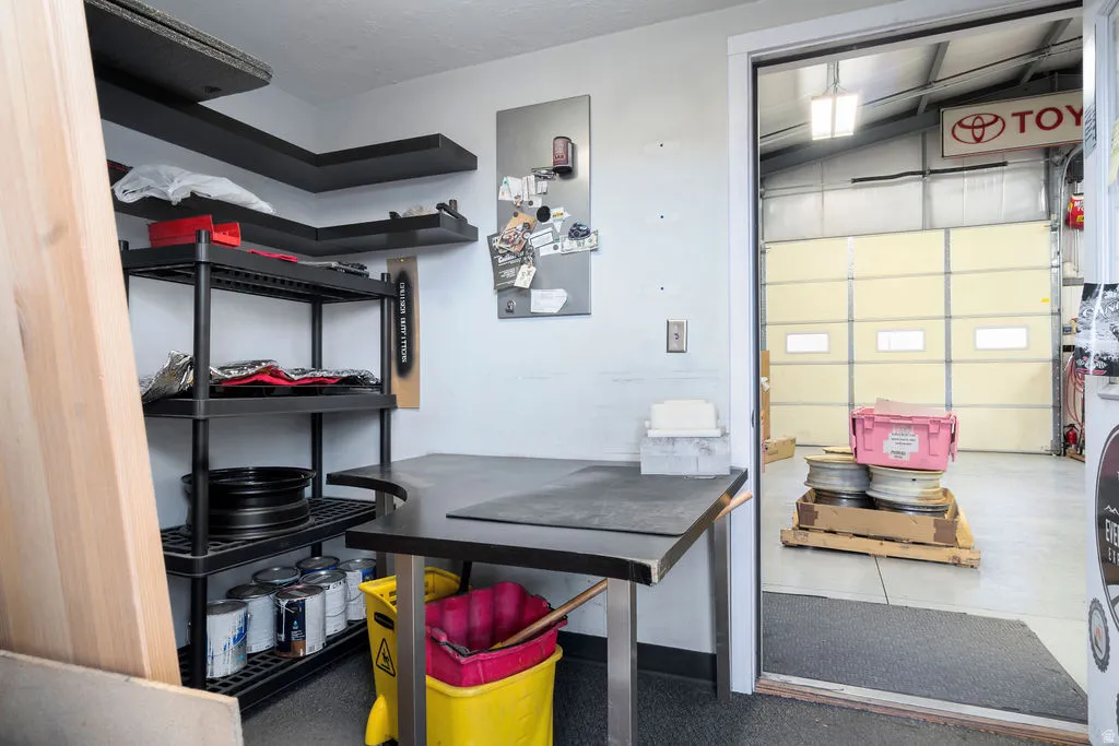 Utility room featuring built-in L-shaped shelving, wall-mounted floating shelves, and a dark-toned countertop workstation