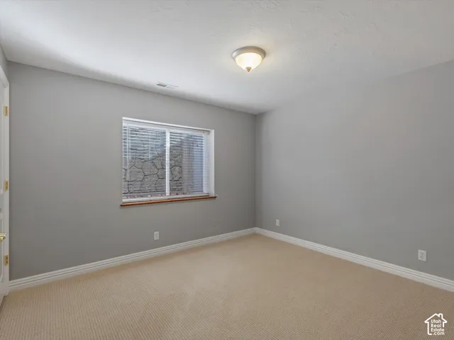 Carpeted bedroom featuring a window with integrated blinds and a stone-lined window well