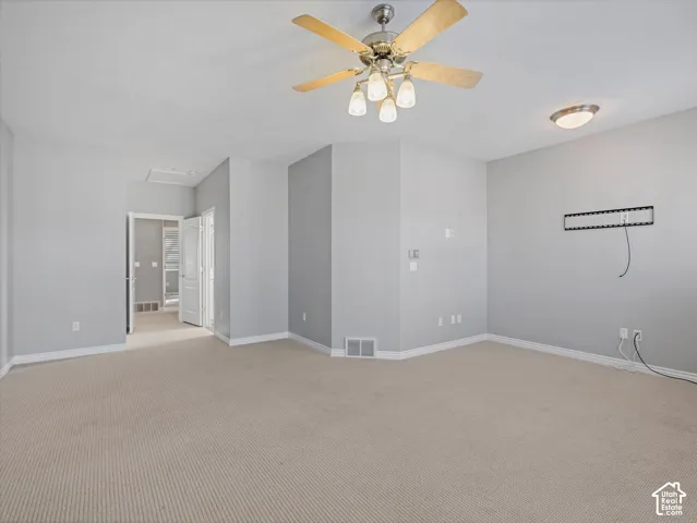 Spacious room featuring neutral carpeting, light gray wall paint, and white baseboards