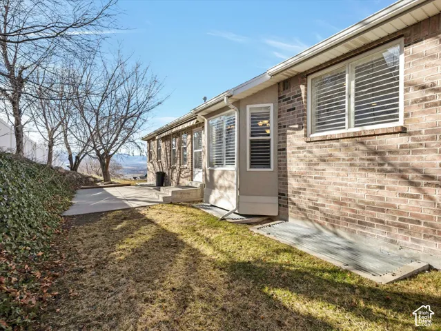 Rear exterior featuring brick and stucco siding with multiple windows