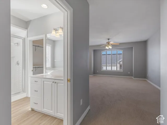 Primary bedroom featuring neutral carpeting and an arched window with plantation shutters. en-suite