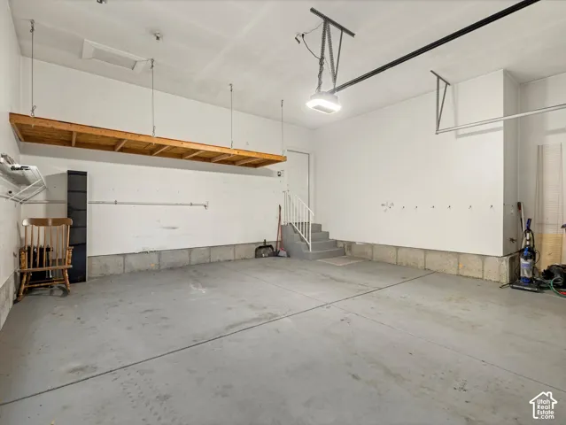 Spacious garage featuring a concrete floor, built-in overhead storage, and an interior staircase providing building access