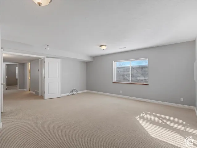 large basement bedroom featuring light gray walls, neutral carpet, and white trim
