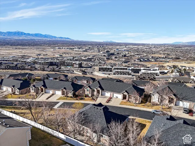 Sprawling urban landscape under a clear sky, featuring a vast expanse of residential developments and distant mountains