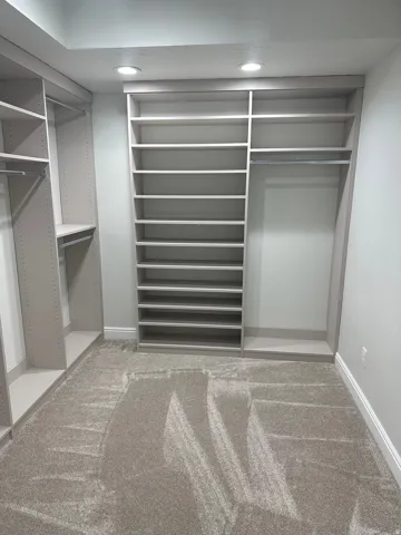 Walk-in closet featuring extensive built-in shelving, multiple hanging rods, recessed lighting, and light-toned carpeting