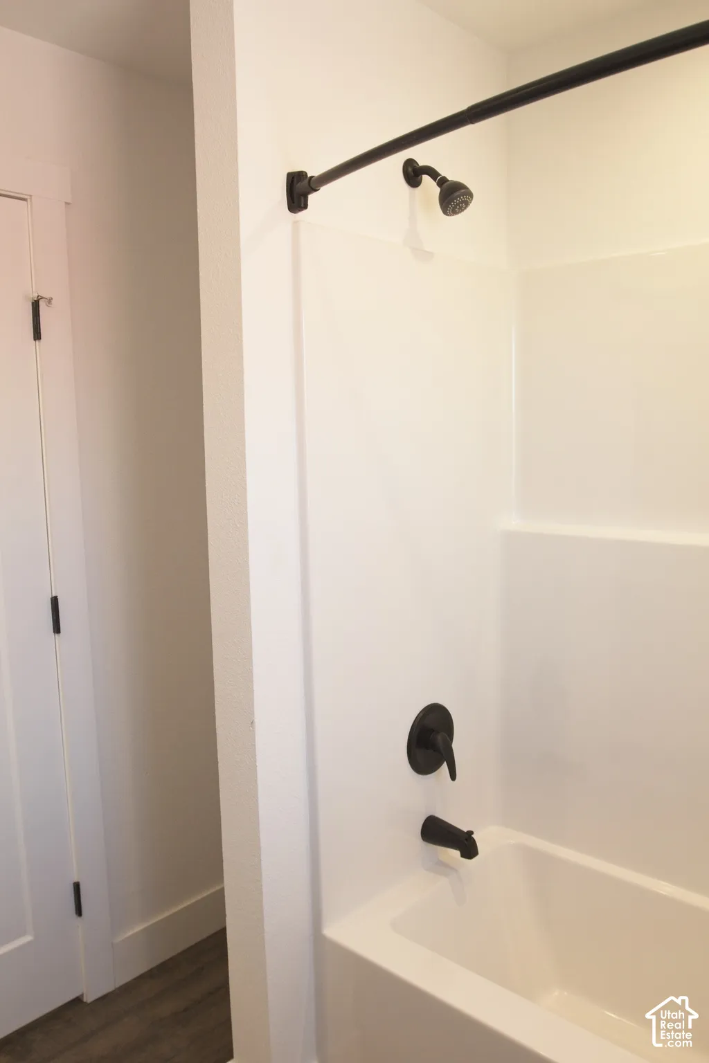 Bathtub and shower surround featuring a matte black single-handle faucet and showerhead, complemented by matching black hardware