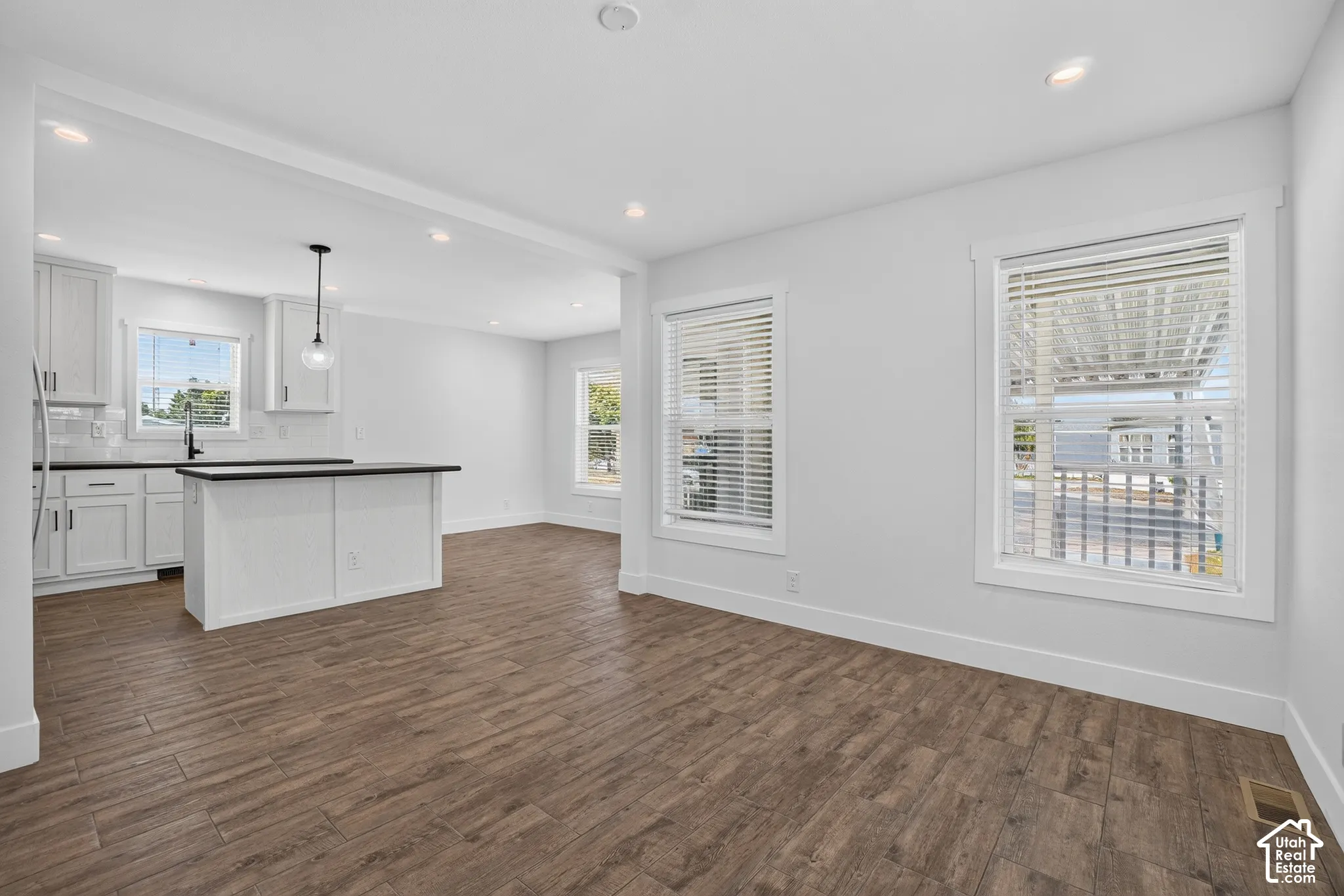 Open-concept living space featuring wood-finish flooring, recessed lighting, and bright white walls