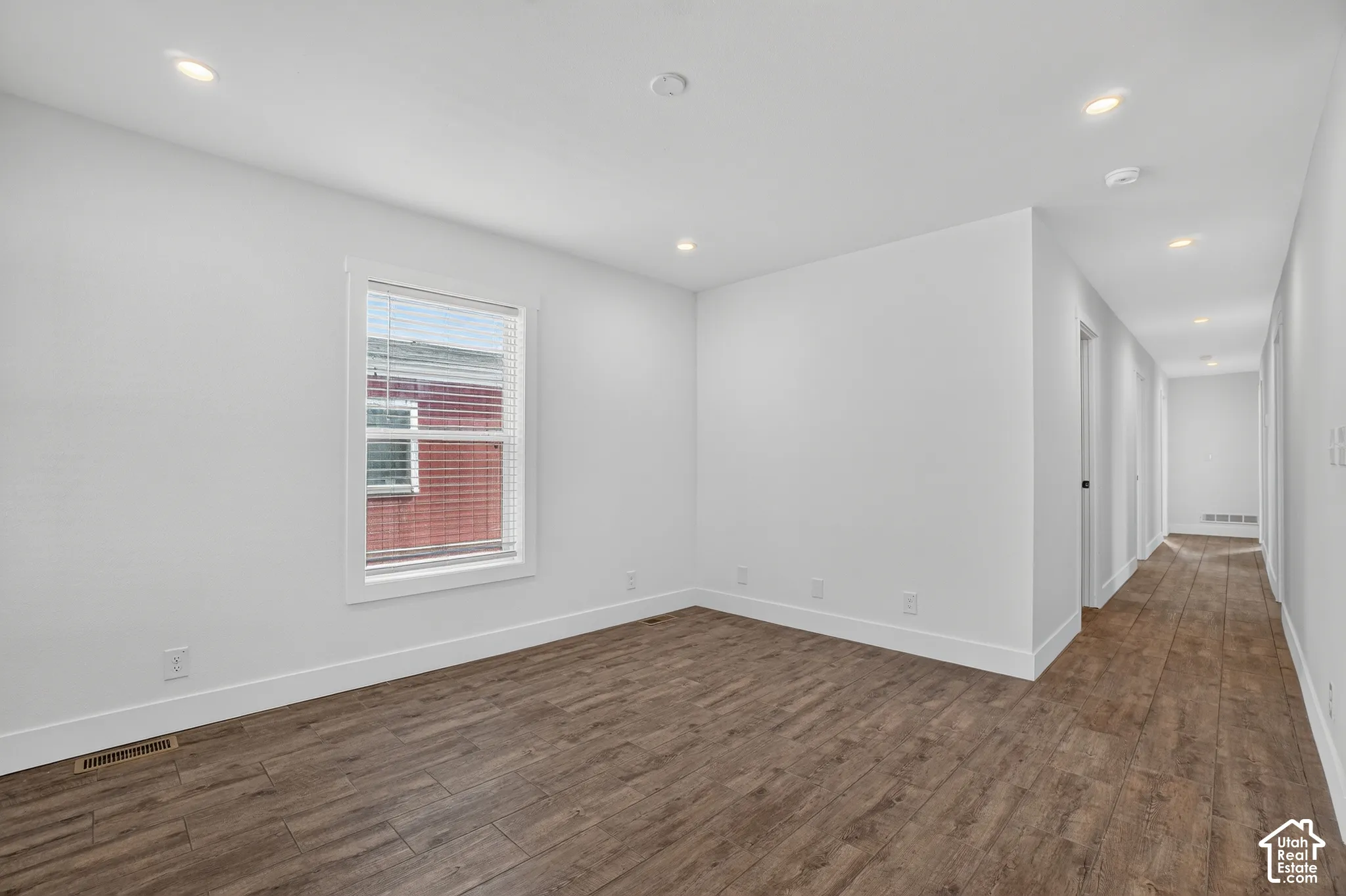 Spacious room featuring wood-finish flooring, white baseboards, and neutral wall paint