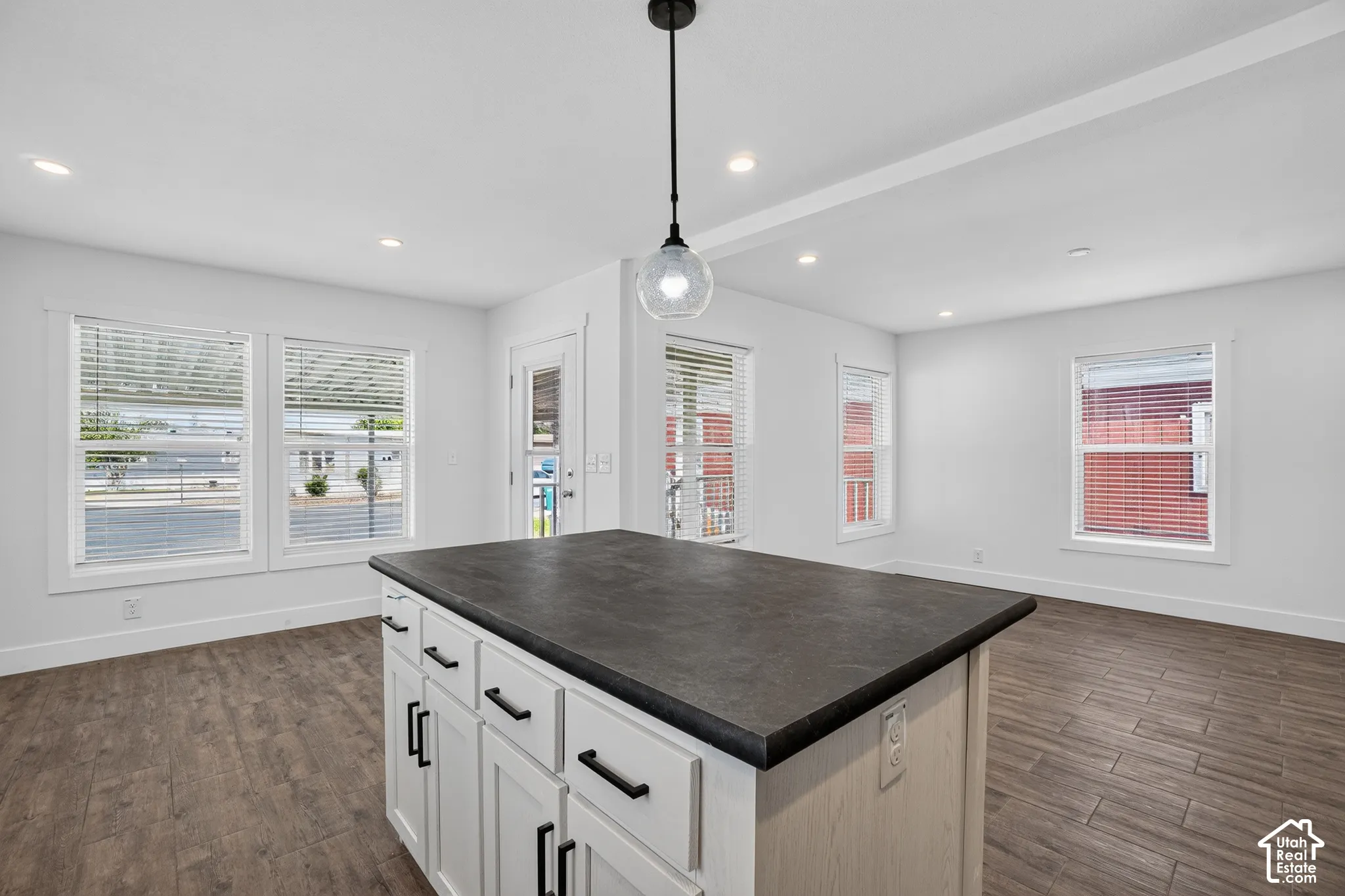 Central kitchen island featuring a dark countertop and white cabinetry with matte black hardware