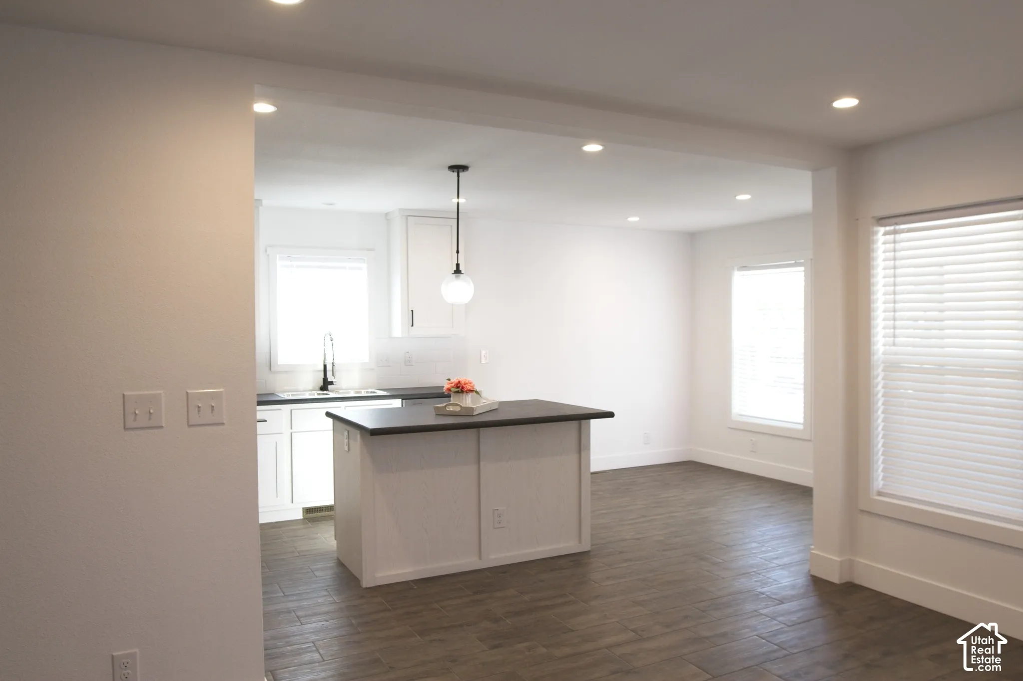 Kitchen featuring white shaker-style cabinetry, a center island with a dark countertop, wood-finish flooring, recessed lighting, and a modern pendant light