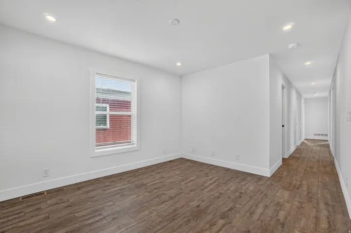 Spacious room featuring wood-finish flooring, white baseboards, and neutral wall paint