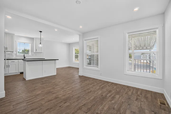 Open-concept living space featuring wood-finish flooring, recessed lighting, and bright white walls