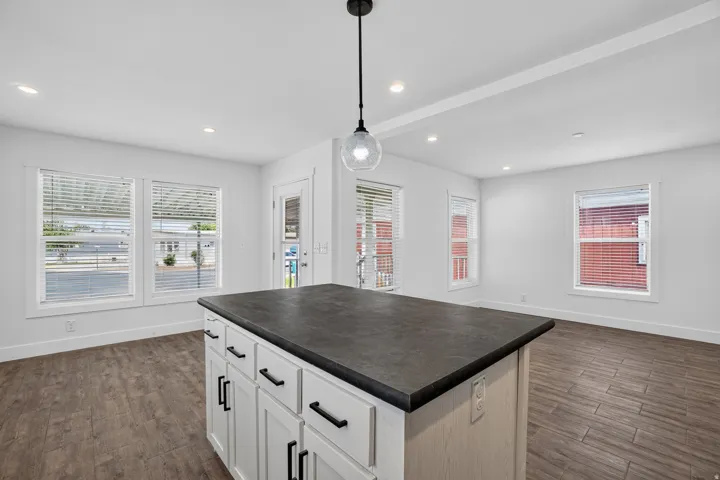 Central kitchen island featuring a dark countertop and white cabinetry with matte black hardware