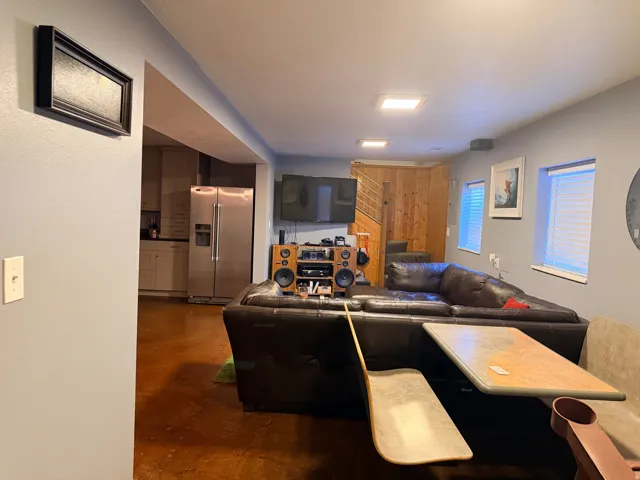 Open-concept living area with polished concrete flooring, recessed lighting, and a partial wood-paneled wall feature