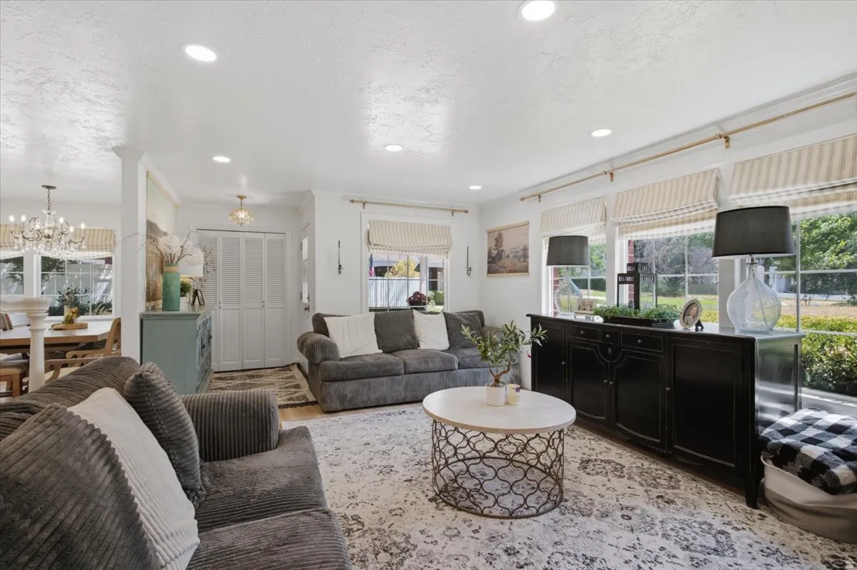 Spacious living area featuring recessed lighting, large windows with striped Roman shades, and a wide cased opening into an adjacent dining space