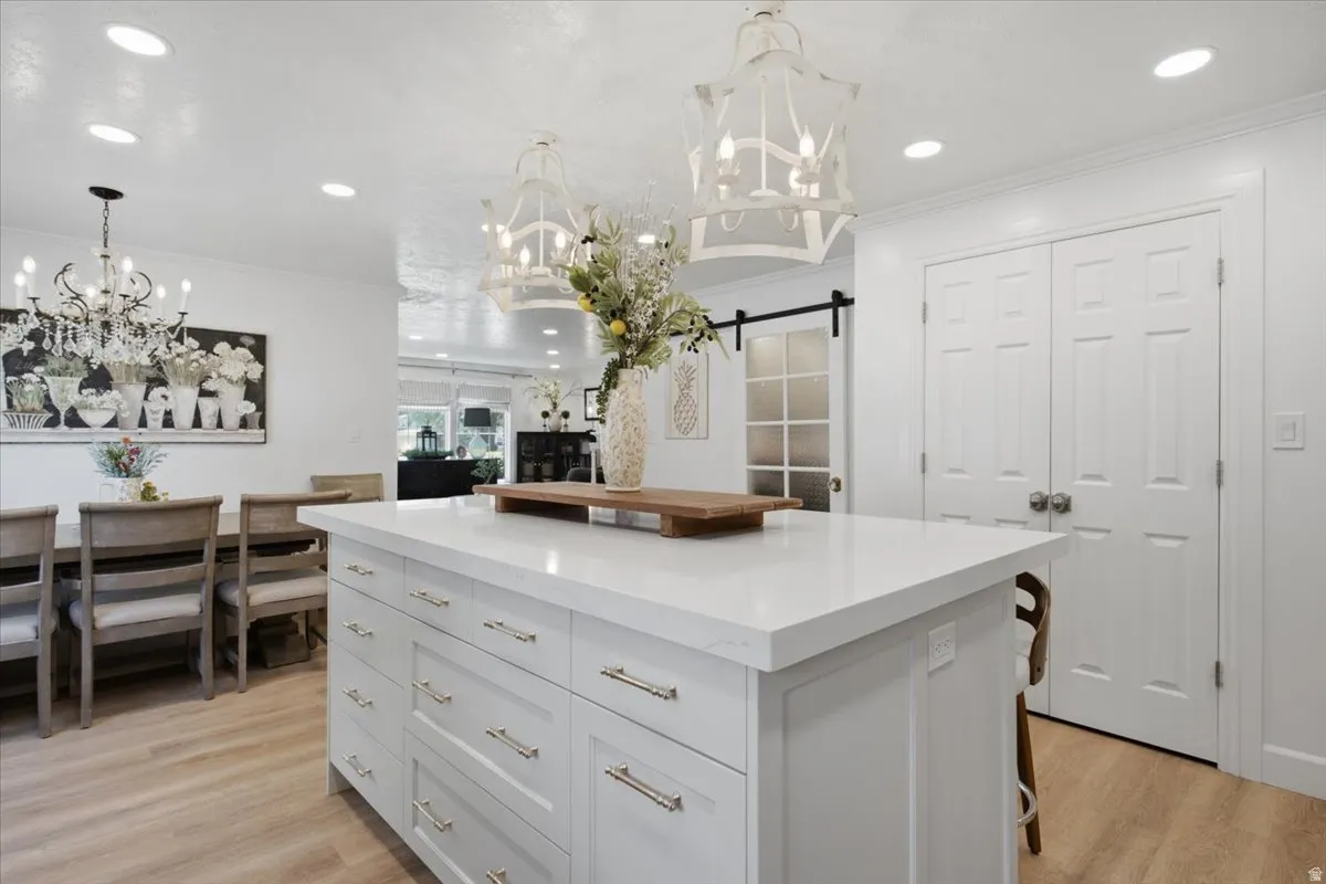 Kitchen island featuring a white countertop, recessed lighting, and wood-finish flooring
