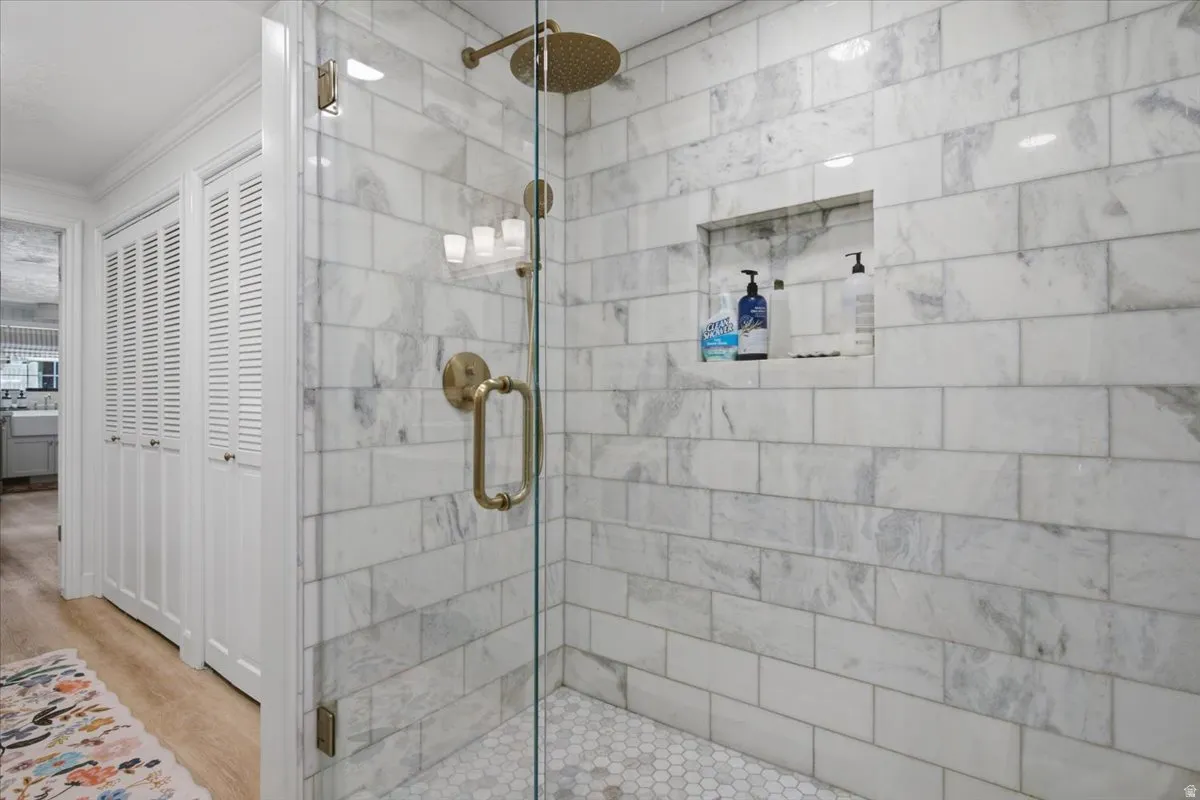 Glass-enclosed shower featuring white subway tile walls, a built-in shower niche, and a hexagonal tile floor