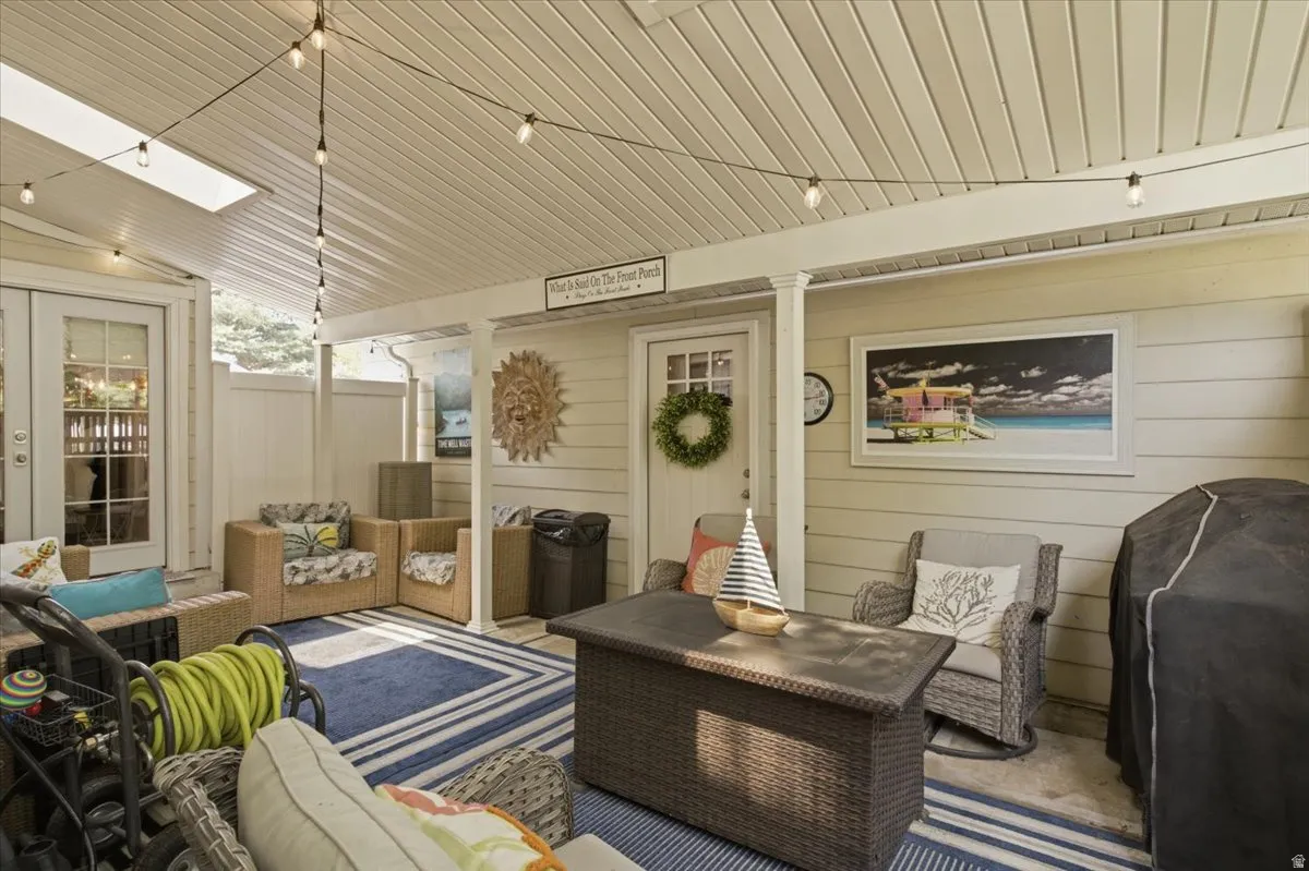 Covered porch featuring a skylight, string lighting, and direct access through a white-framed glass door
