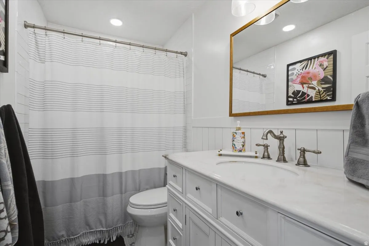 White vanity with paneling and drawer storage, featuring a white countertop and basin sink