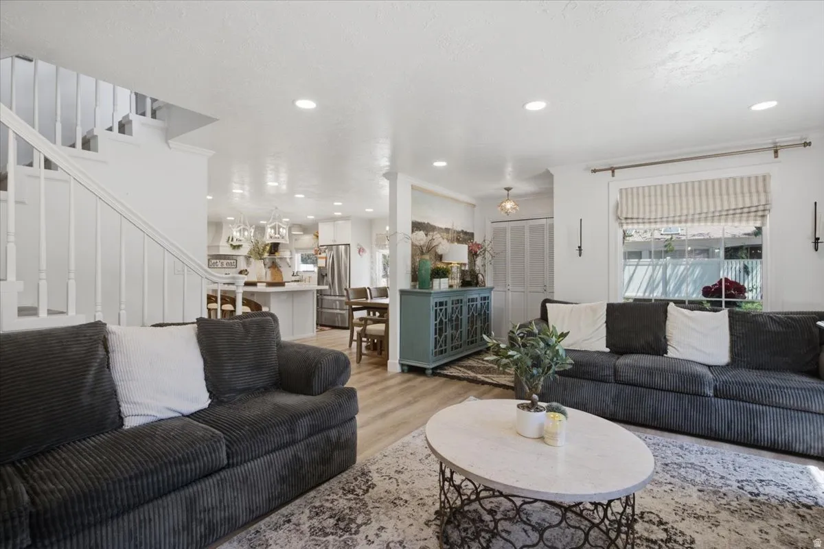 Bright living area featuring wood-finish flooring, recessed lighting, and a white staircase with spindle balusters
