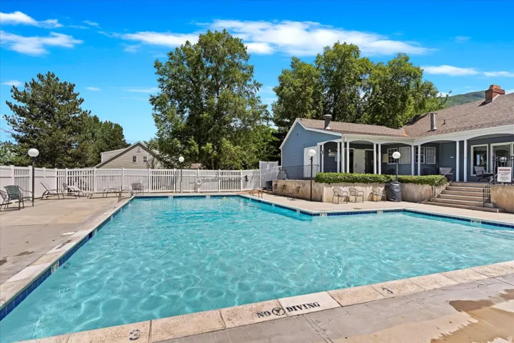 Outdoor swimming pool with integrated steps, surrounded by a concrete deck and white fencing
