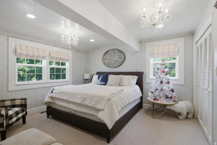 Well-appointed interior space featuring two windows, recessed lighting, two chandeliers, and carpeted flooring
