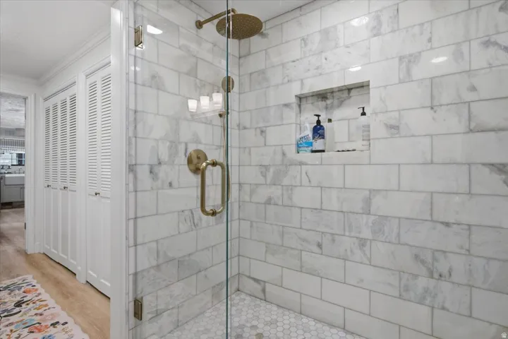 Glass-enclosed shower featuring white subway tile walls, a built-in shower niche, and a hexagonal tile floor