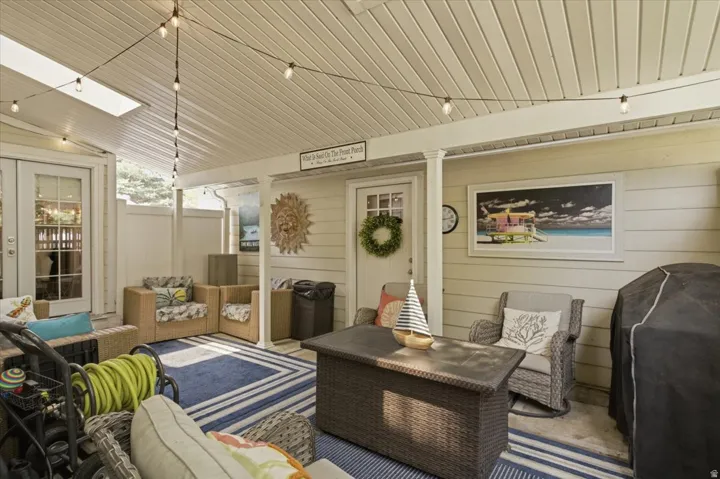 Covered porch featuring a skylight, string lighting, and direct access through a white-framed glass door