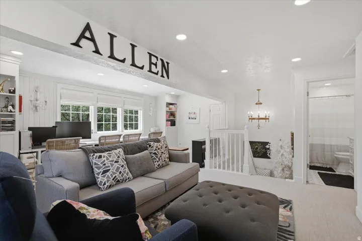 Open-concept living space featuring recessed lighting, a built-in desk area with multiple windows, a stairway with white balusters, and a visible bathroom entrance with a glass shower door