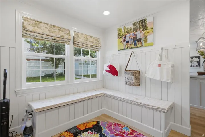 Built-in corner bench seating with cushioned tops, framed by two double-hung windows featuring patterned Roman shades