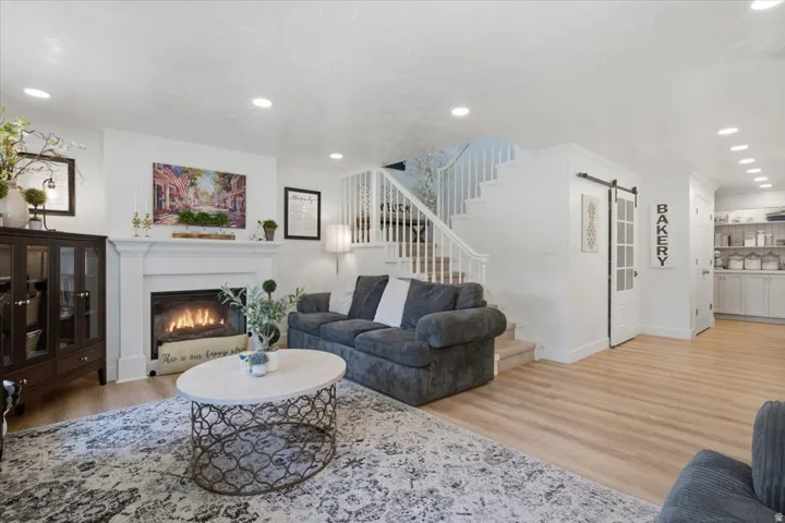Living area featuring a white mantel fireplace, light wood-finish flooring, and recessed ceiling lighting