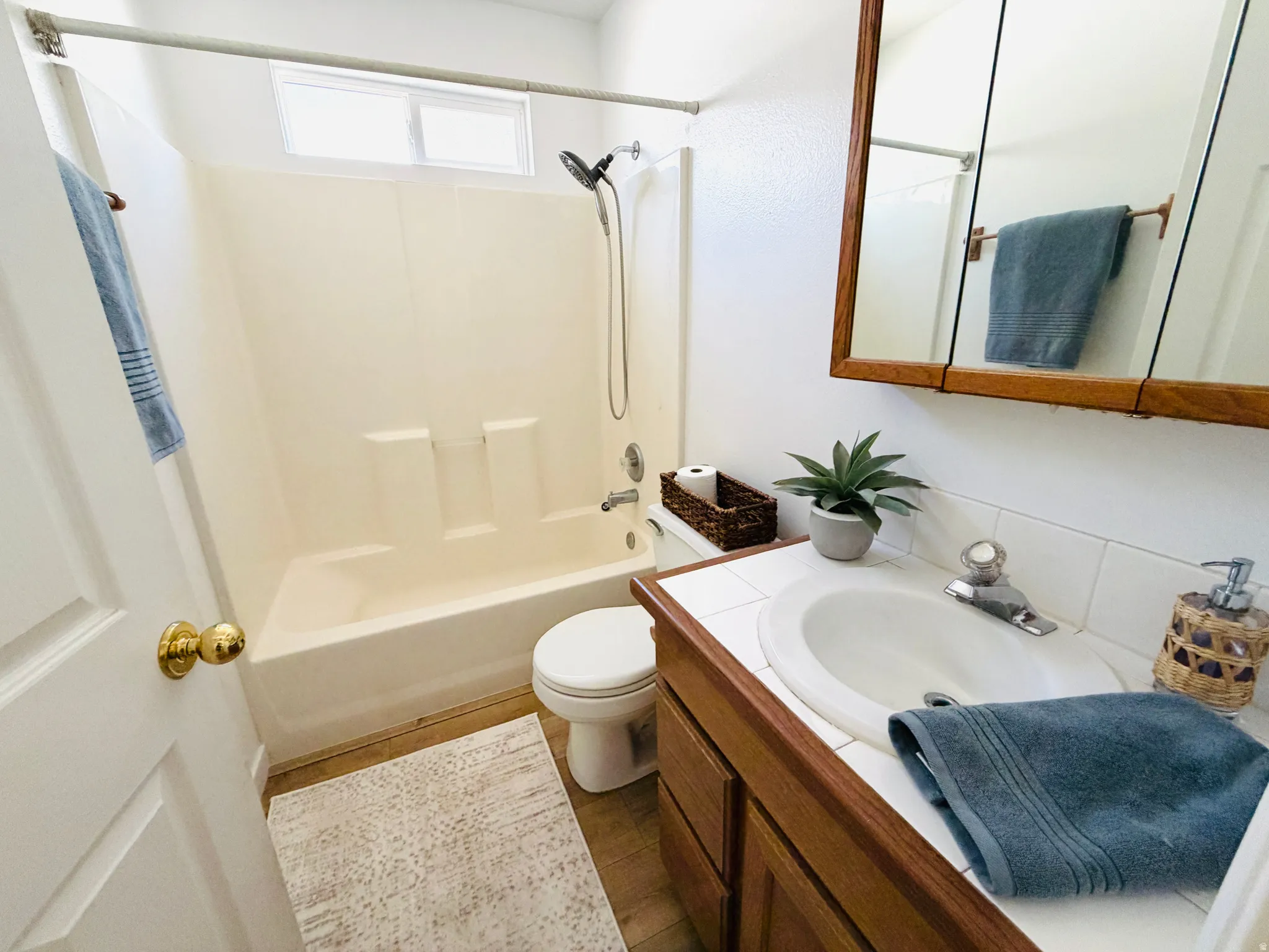 Bathroom vanity with wood-finish cabinetry, integrated sink, and white tile countertop
