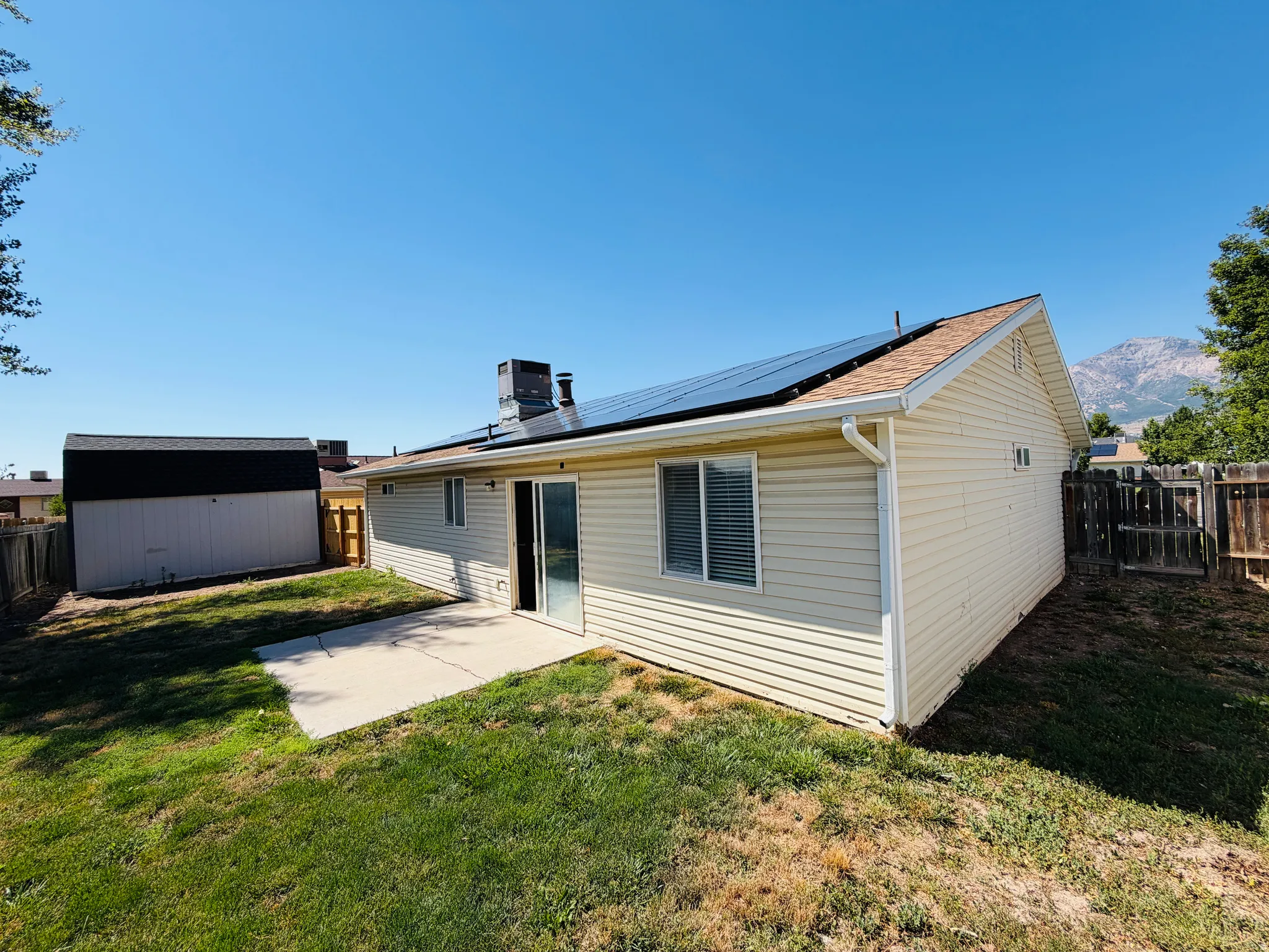 Rear exterior featuring a patio, sliding glass door, and solar panels