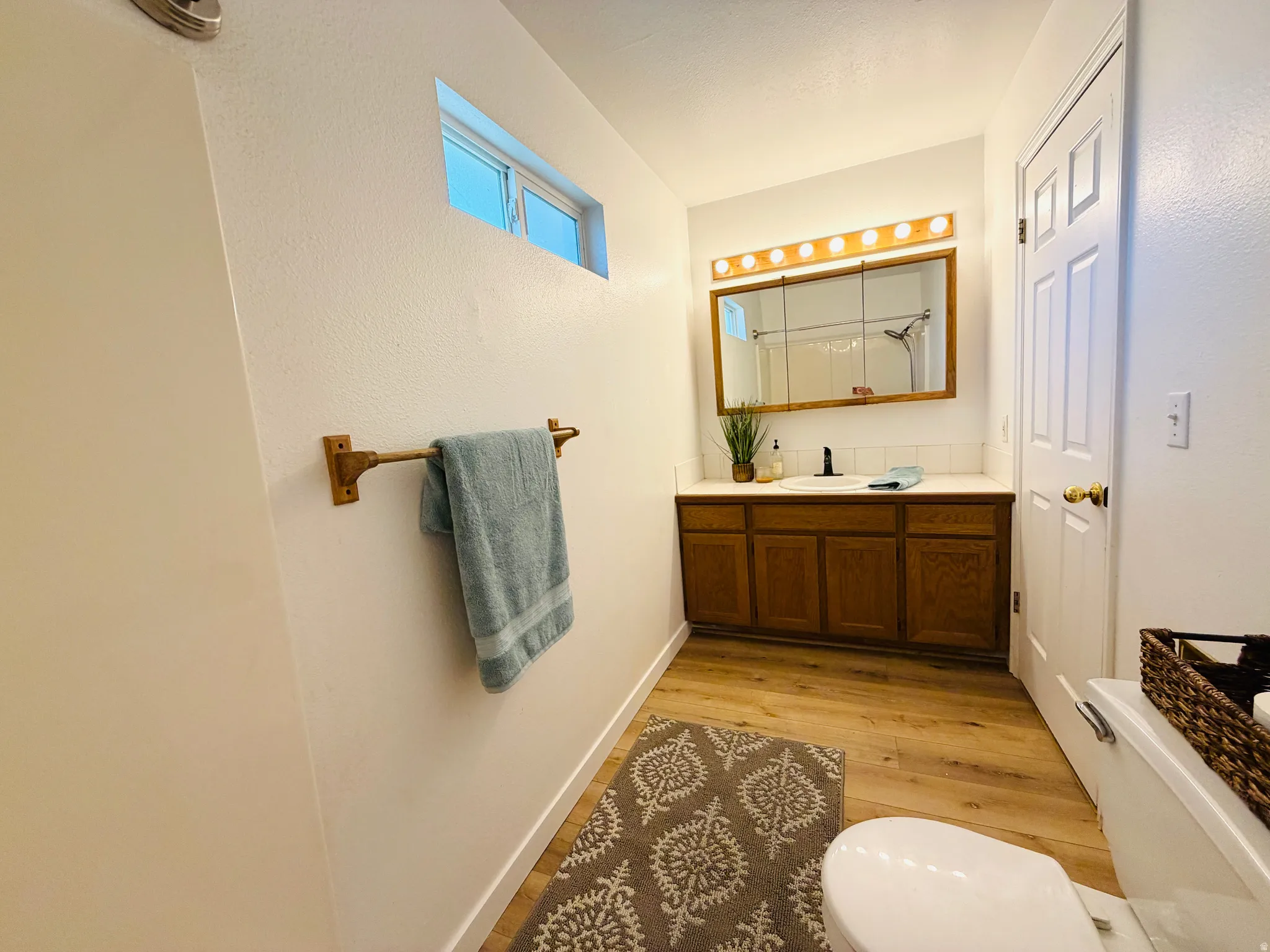 Bathroom featuring a wood-finish vanity with a white countertop and rectangular sink