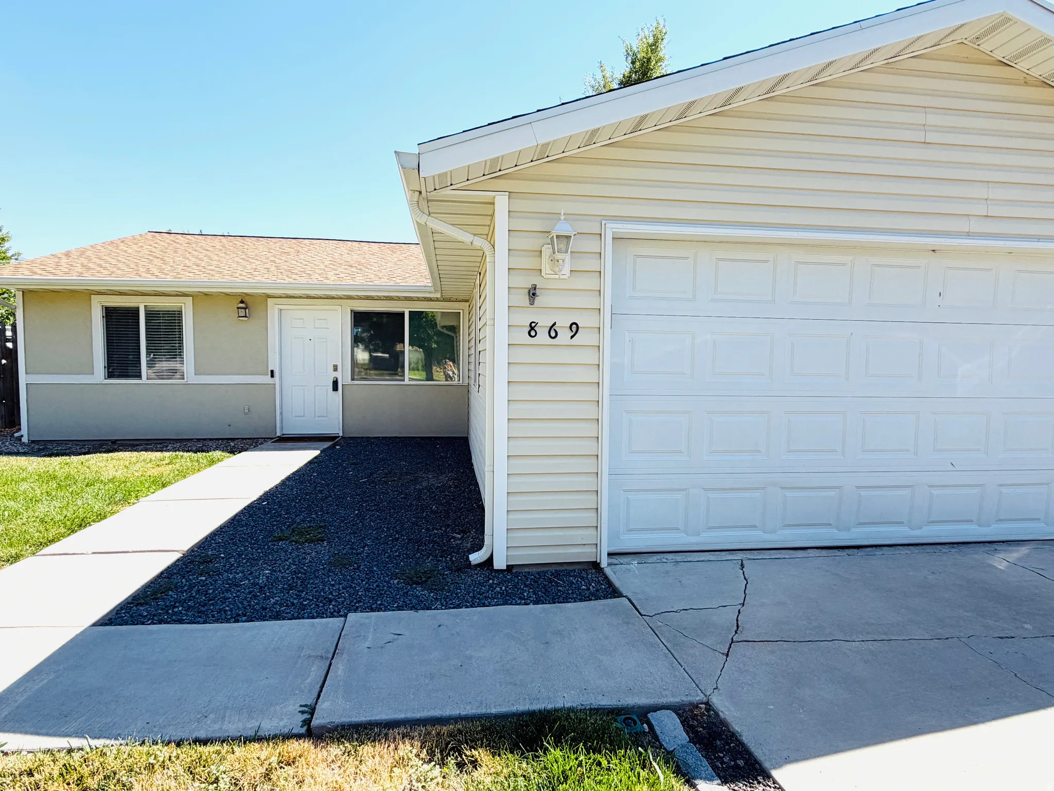 Single-story exterior with light beige siding and a white garage door