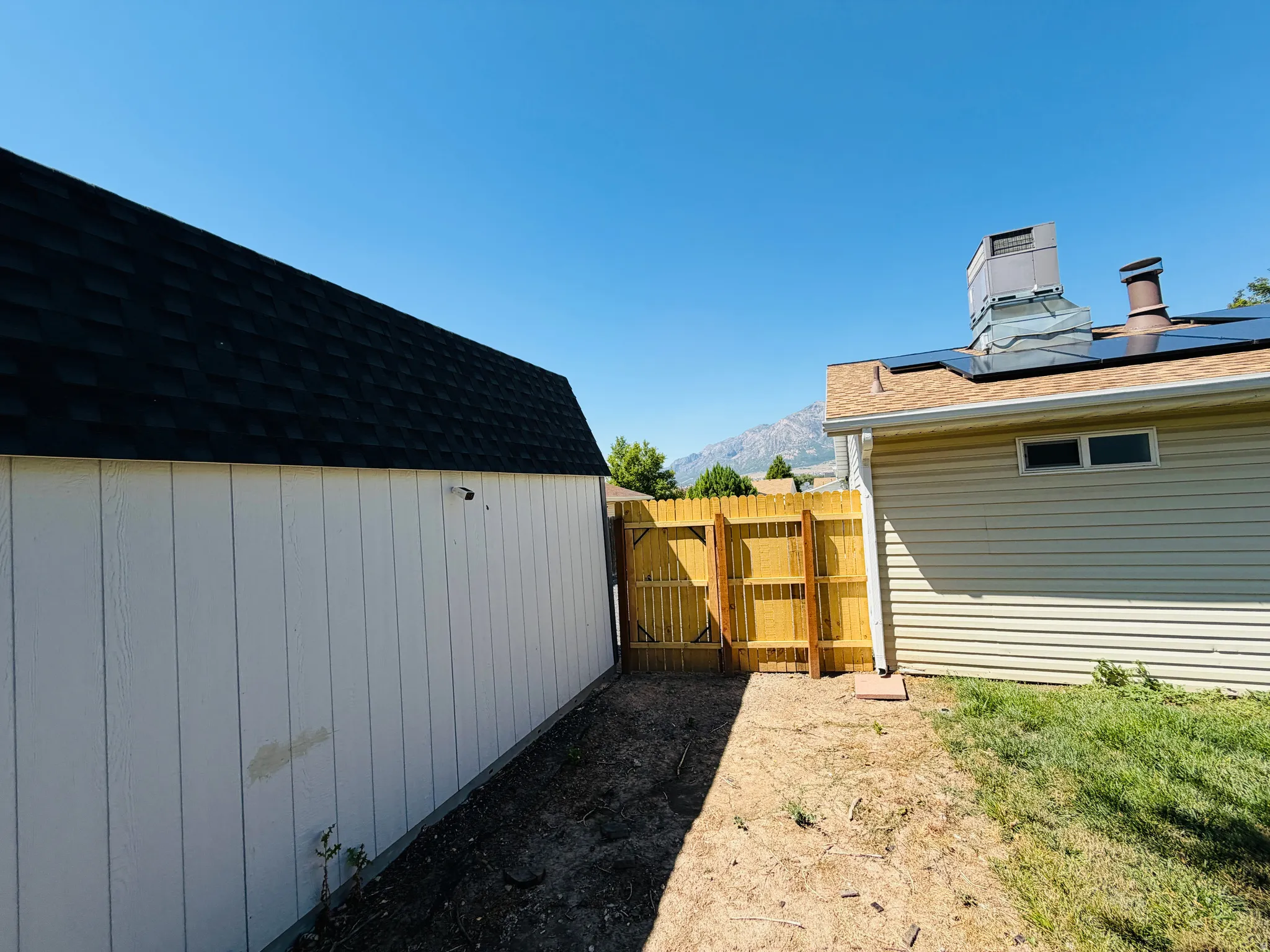 Detached storage shed with a dark shingle roof and white vertical siding