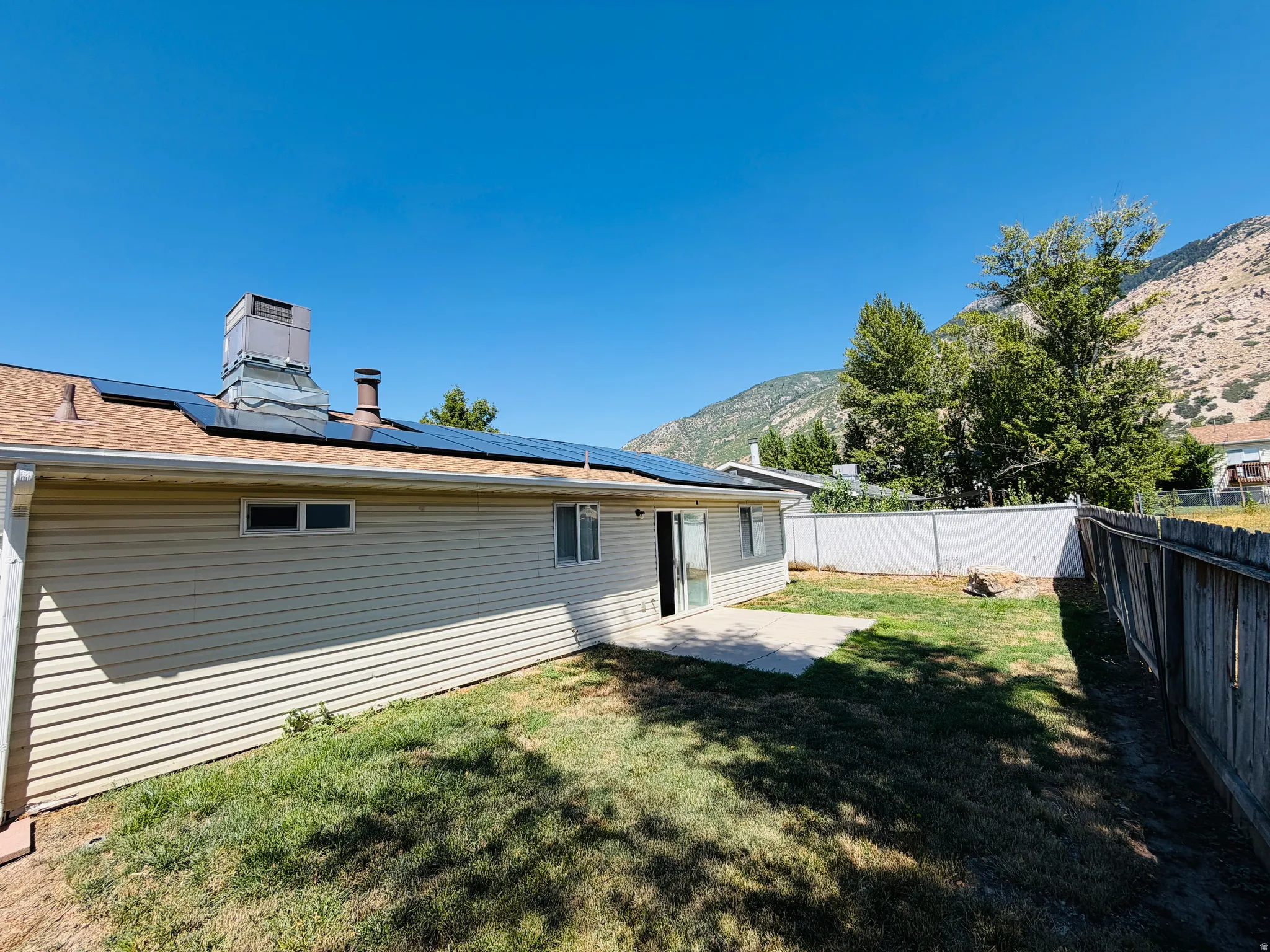Backyard with a concrete patio, lawn, and wood privacy fence