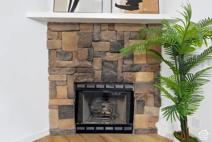 Corner fireplace featuring a multi-tonal stacked stone surround, rectangular white mantel, and black metal firebox