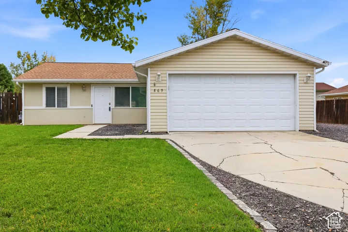 Single-story exterior featuring light-toned horizontal siding, a two-car attached garage, a concrete driveway, and a front lawn with stone-edged borders