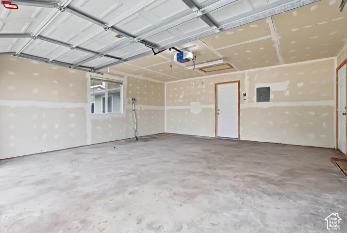 Multi-car garage featuring a concrete floor, automated overhead door, side-entry door, and natural light via a window