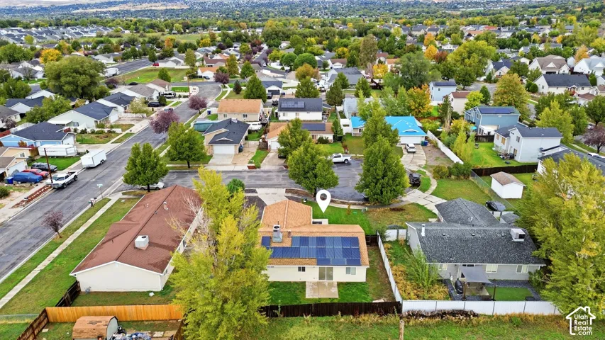 Aerial perspective featuring a detached residential property with solar panel array, shingled roofing, rear concrete patio, and fenced perimeter