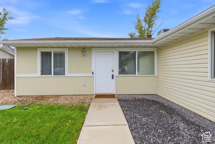 Exterior featuring horizontal siding, multi-pane windows, a concrete walkway, and an attached outdoor light fixture