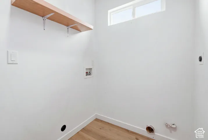Utility space featuring wood-finish flooring, a wall-mounted floating shelf, and a high-positioned horizontal window